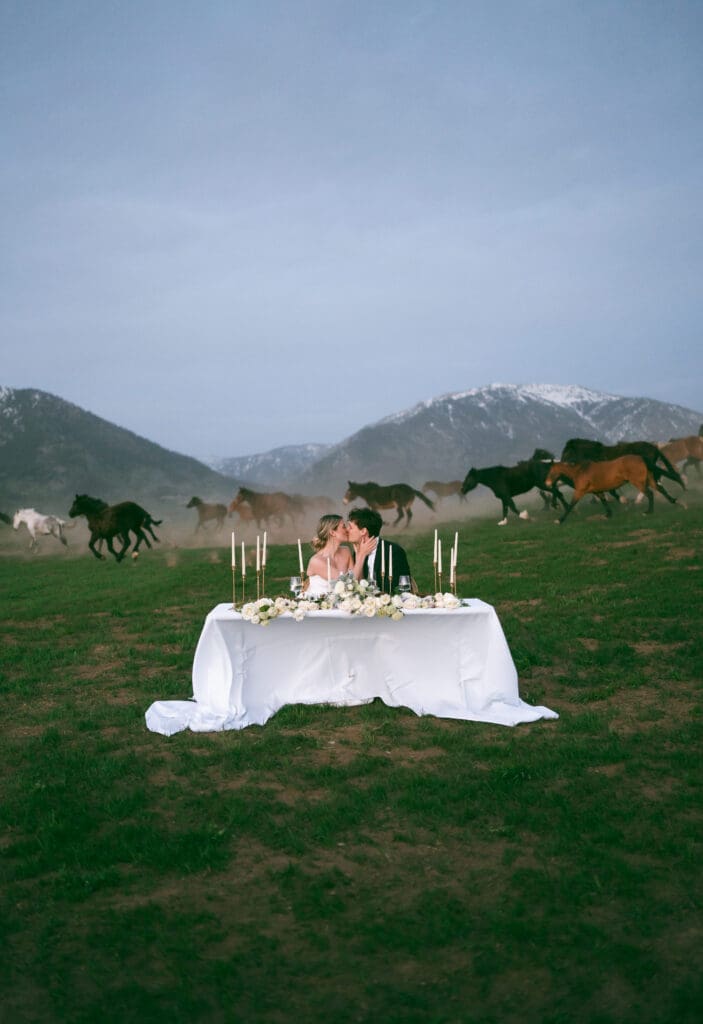 bride and groom at sweetheart table with horses running in the background