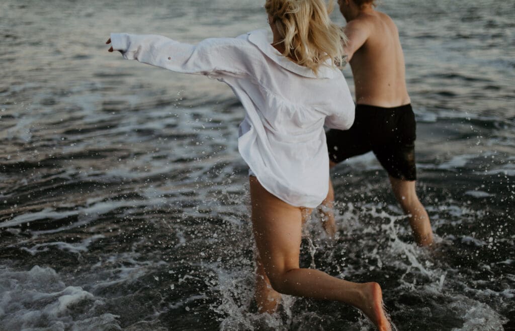 couple running through waves in motion photography