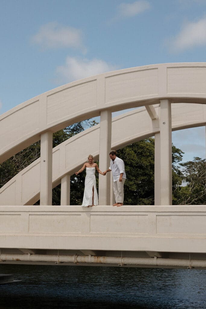 bride and groom jumping off bridge in oahu hawaii on wedding day