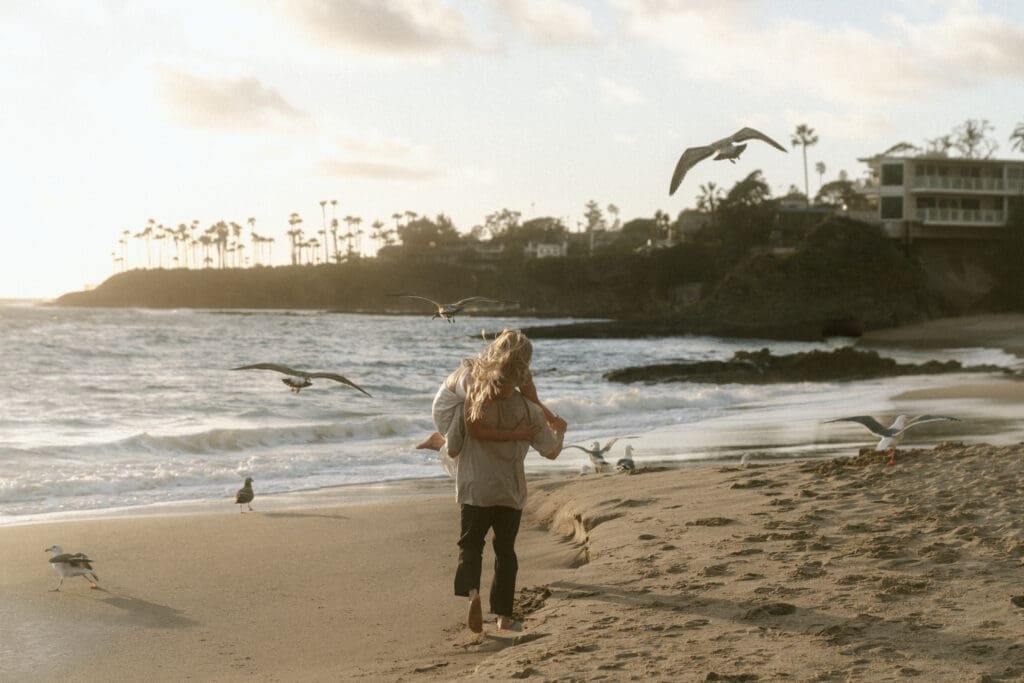 couple on the beach in California with seagulls flying away