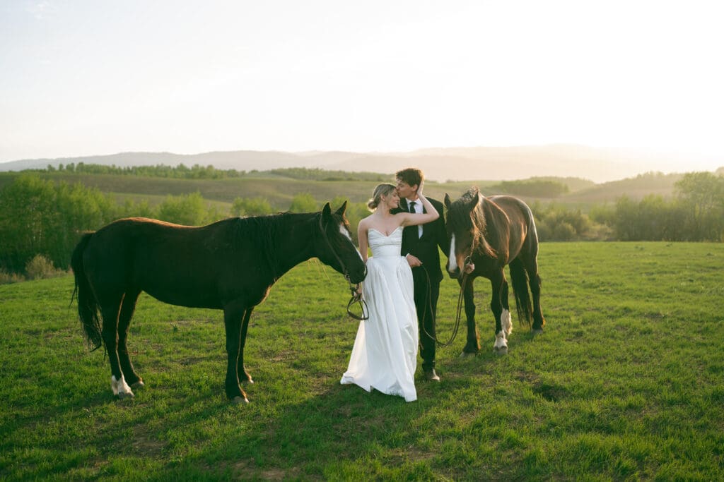 couple getting married holding horses at sunset in wyoming